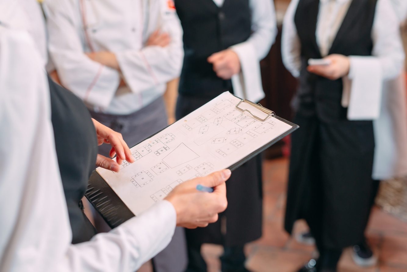 restaurant manager and his staff in kitchen. interacting to head chef in commercial kitchen